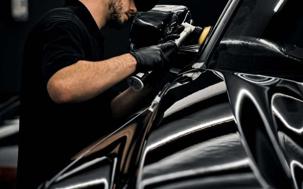 A detailer applying protection to a car body panel by hand
